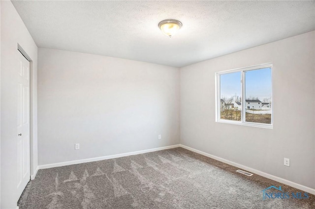 spare room with visible vents, carpet flooring, a textured ceiling, and baseboards