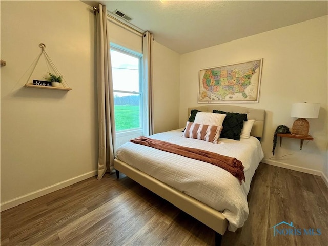 bedroom featuring visible vents, wood finished floors, and baseboards