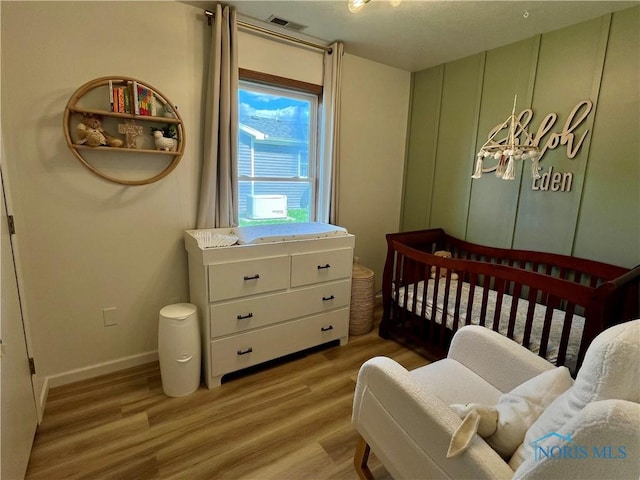bedroom with baseboards, visible vents, and light wood finished floors