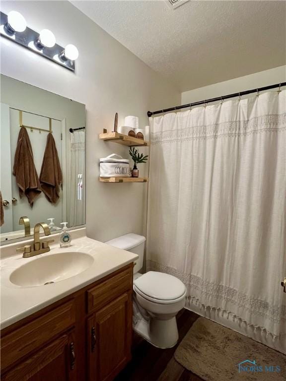 bathroom with wood finished floors, toilet, vanity, curtained shower, and a textured ceiling