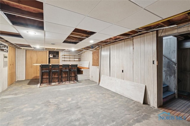 below grade area with a dry bar, wooden walls, and stairway