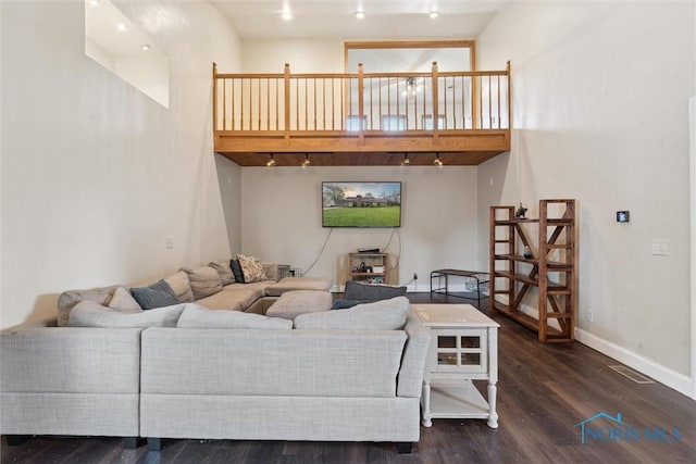 living area featuring baseboards, a high ceiling, wood finished floors, and visible vents