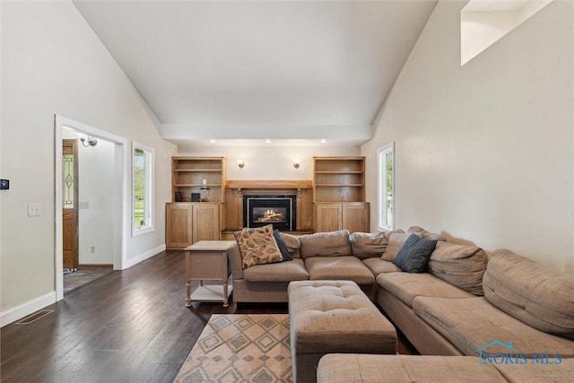 living room featuring a glass covered fireplace, visible vents, dark wood-style flooring, and a wealth of natural light