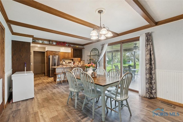 dining room featuring a notable chandelier, beamed ceiling, visible vents, and wood finished floors
