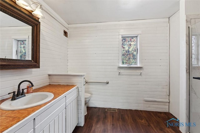 full bathroom featuring vanity, toilet, wood finished floors, visible vents, and a stall shower