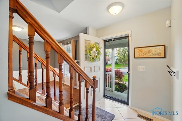 foyer entrance with visible vents, baseboards, light tile patterned floors, and stairway