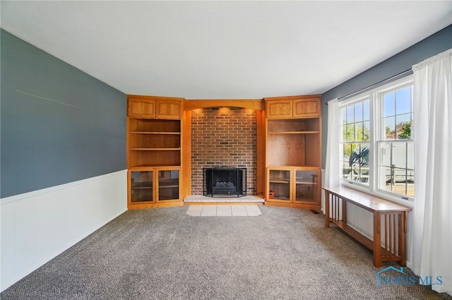 unfurnished living room with wainscoting, carpet, and a fireplace