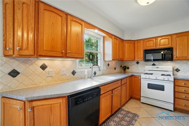 kitchen with brown cabinetry, light countertops, tasteful backsplash, a sink, and black appliances