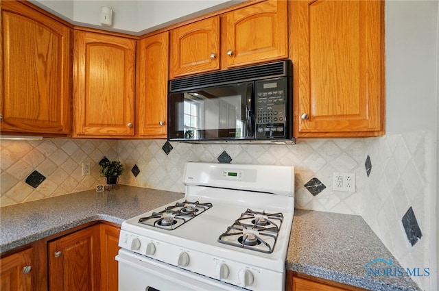 kitchen with black microwave, decorative backsplash, gas range gas stove, and brown cabinets