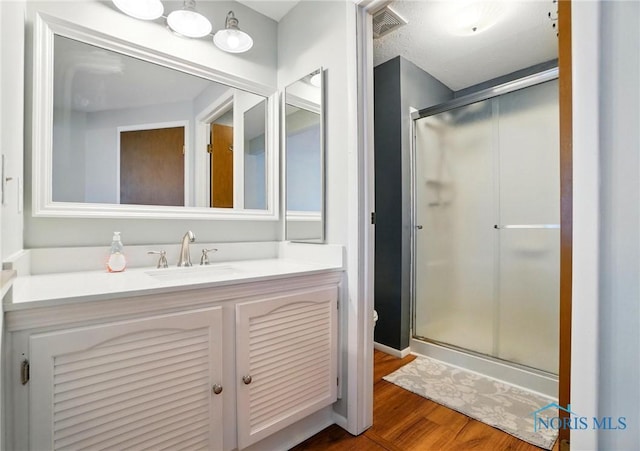 bathroom with toilet, a shower stall, wood finished floors, and vanity