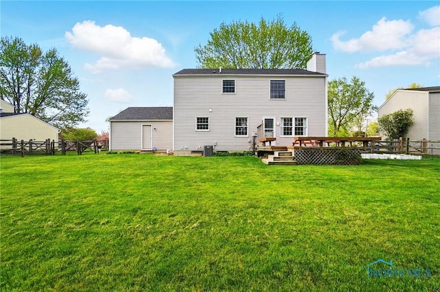 rear view of house with a fenced backyard, a chimney, a yard, and a deck