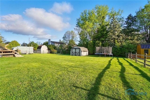 view of yard featuring an outdoor structure, fence, and a storage shed