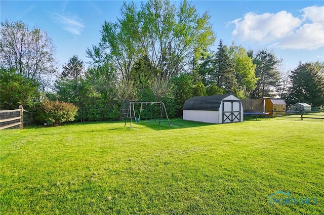 view of yard featuring a storage shed, fence, an outbuilding, and a playground