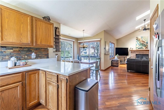 kitchen with lofted ceiling, open floor plan, light wood finished floors, a peninsula, and a ceiling fan