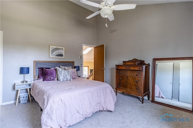 carpeted bedroom featuring a towering ceiling, a ceiling fan, and baseboards