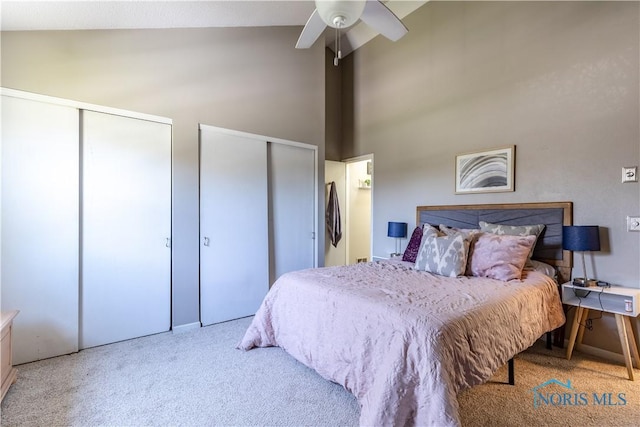 bedroom with two closets, ceiling fan, high vaulted ceiling, and carpet floors