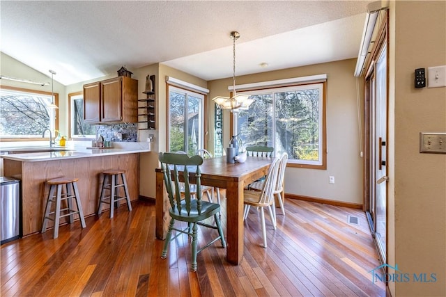 dining room featuring a chandelier, a wealth of natural light, hardwood / wood-style flooring, and baseboards