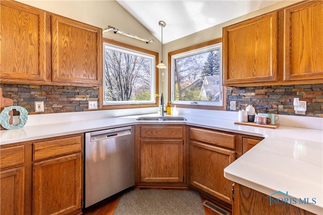 kitchen with stainless steel dishwasher, vaulted ceiling, backsplash, a sink, and visible vents