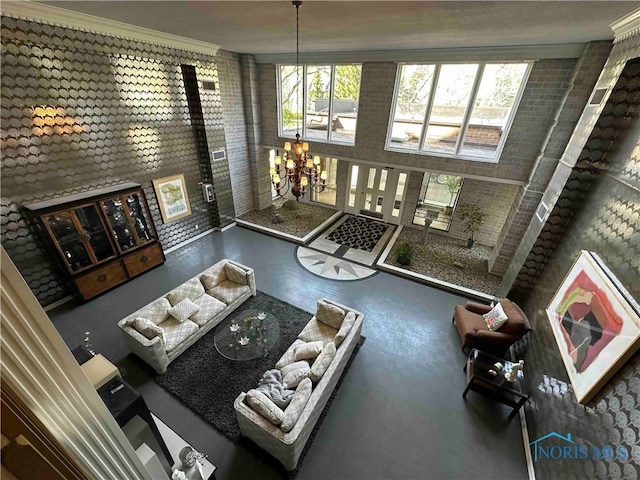 living area featuring a healthy amount of sunlight, brick wall, an inviting chandelier, and crown molding