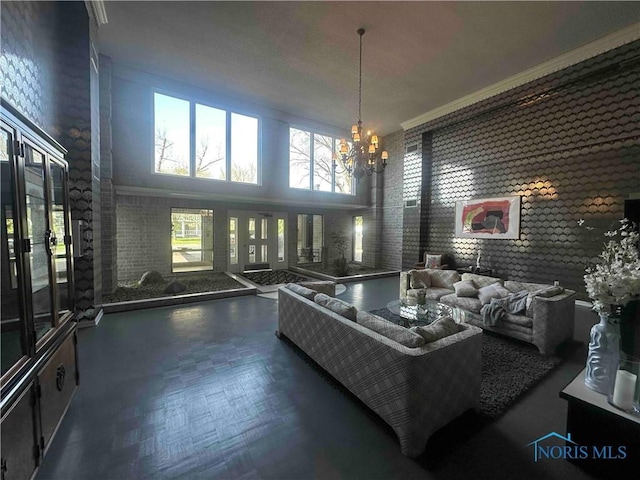 living area featuring an inviting chandelier, crown molding, and a high ceiling