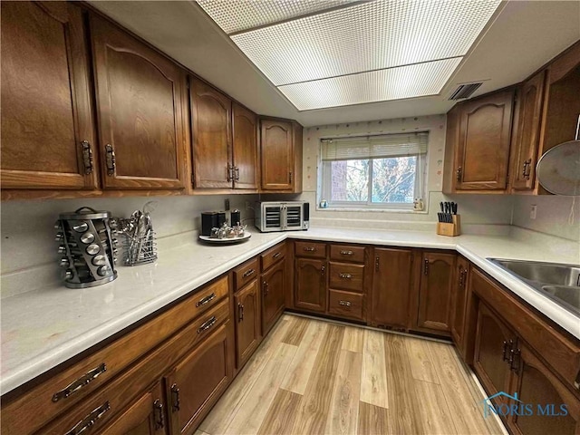 kitchen with visible vents, a toaster, light countertops, and light wood-style flooring