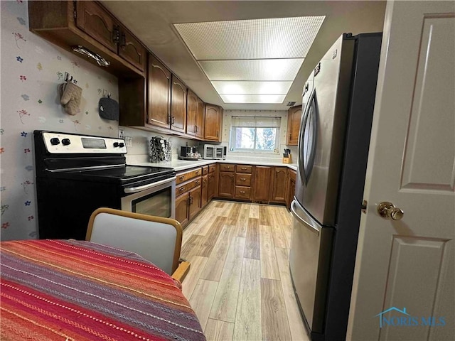 kitchen featuring light countertops, brown cabinets, stainless steel appliances, and light wood-style floors