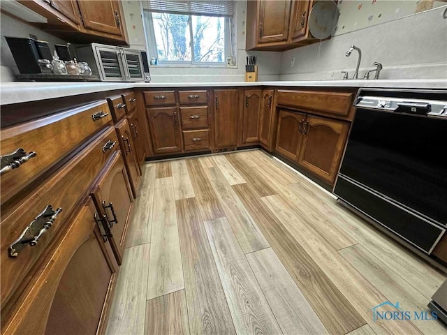 kitchen featuring a toaster, light wood-type flooring, dishwasher, and light countertops