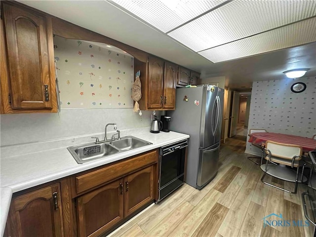 kitchen featuring light wood-style flooring, a sink, light countertops, freestanding refrigerator, and dishwasher