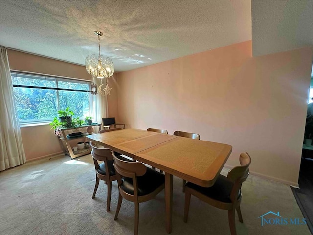 dining space with a chandelier, baseboards, a textured ceiling, and light colored carpet