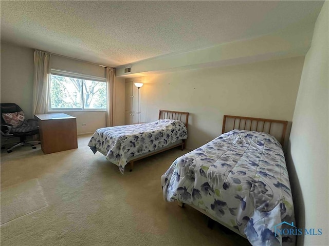 carpeted bedroom featuring visible vents and a textured ceiling