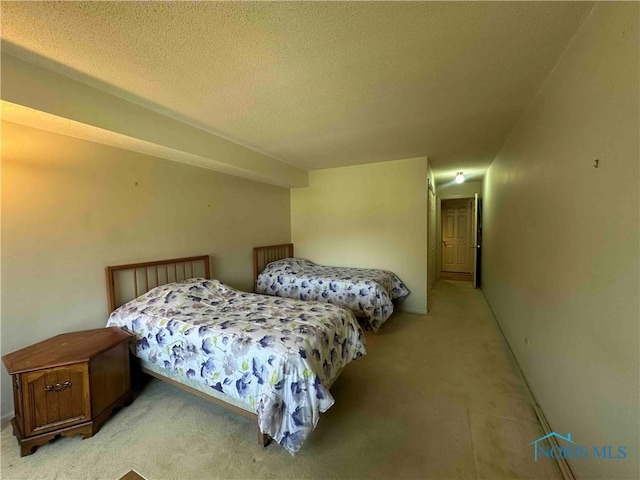 bedroom with a textured ceiling and light colored carpet