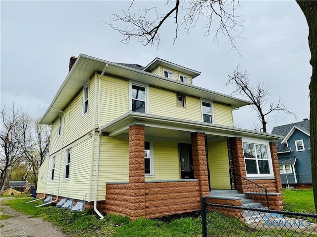 traditional style home featuring a porch, a chimney, and fence