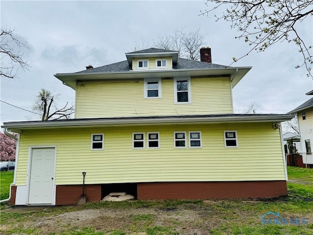 back of property with roof with shingles and a chimney