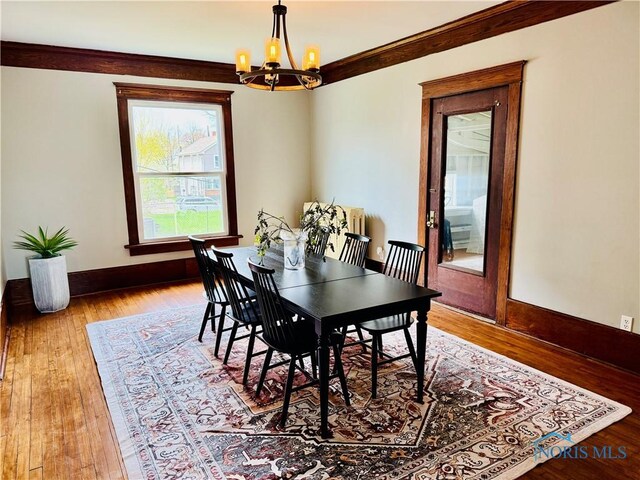 dining space with an inviting chandelier, wood finished floors, and baseboards