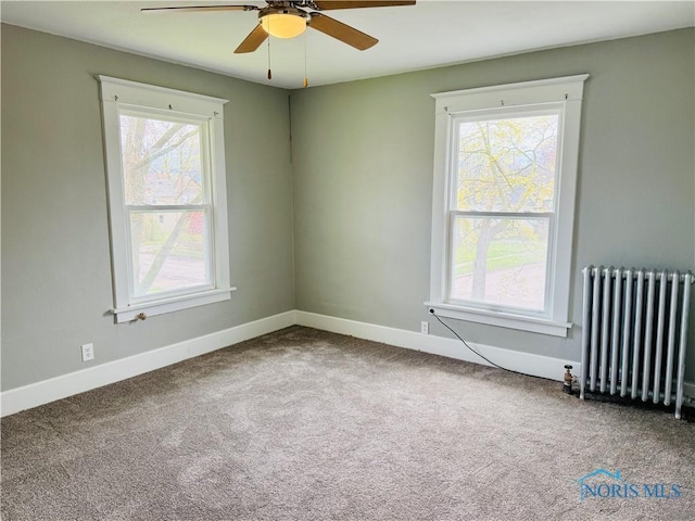 carpeted empty room featuring radiator, ceiling fan, and baseboards