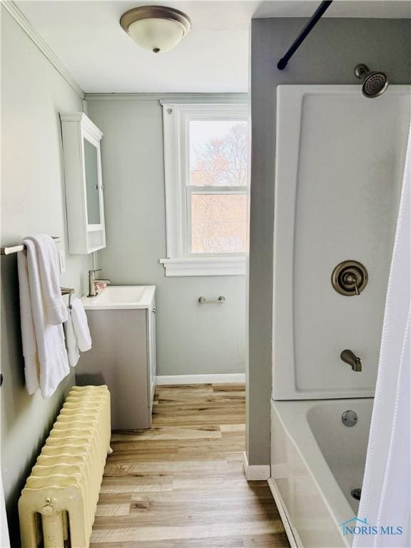 full bath featuring radiator, vanity, shower / bathing tub combination, baseboards, and wood finished floors