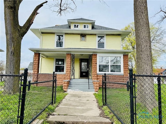 traditional style home featuring a gate, a porch, a front lawn, and a fenced front yard