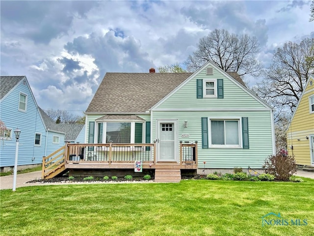 view of front of home with a front yard, a wooden deck, a shingled roof, and a chimney