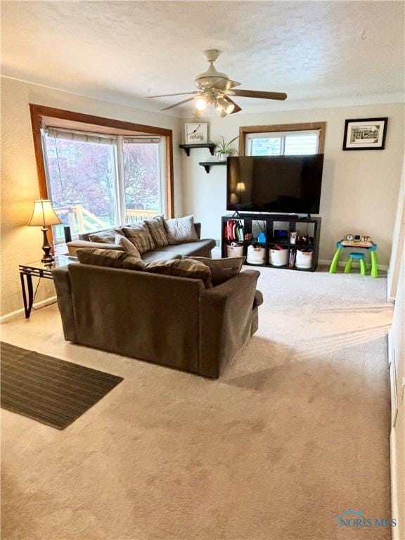 carpeted living room featuring a textured ceiling, ceiling fan, and baseboards