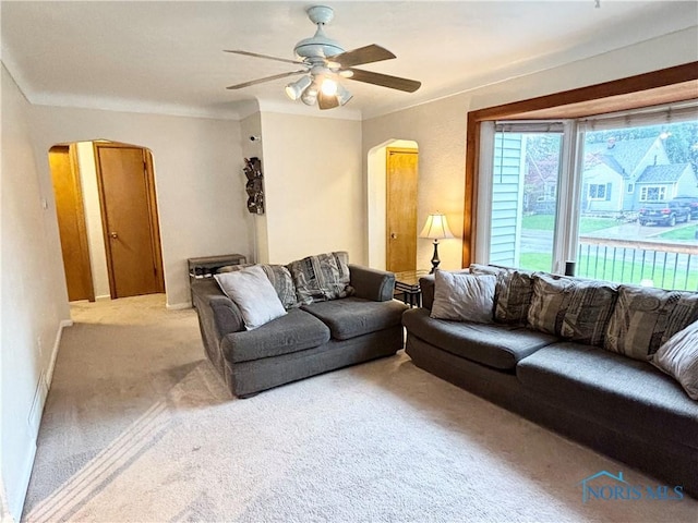 carpeted living room featuring arched walkways and a ceiling fan