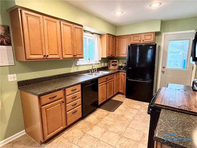 kitchen featuring black appliances, dark countertops, brown cabinets, and a sink