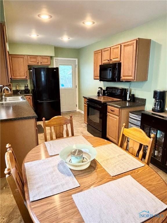 kitchen with black appliances, recessed lighting, a sink, and dark countertops