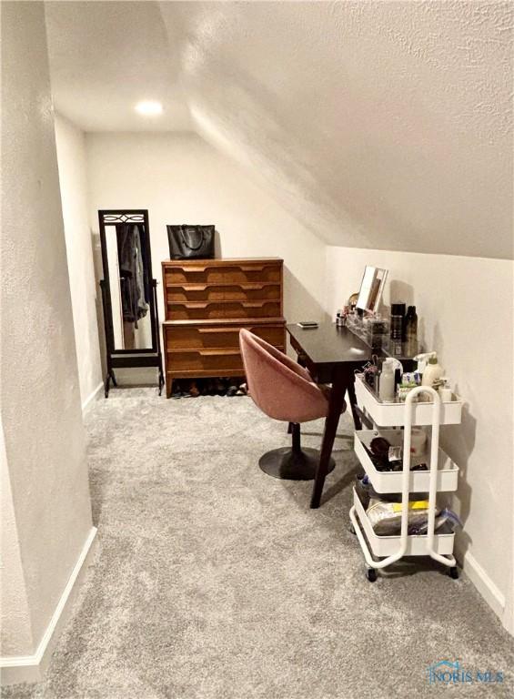 carpeted home office featuring lofted ceiling, a textured ceiling, a textured wall, and baseboards
