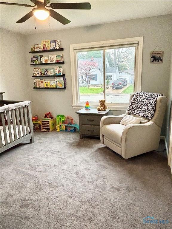 bedroom with a nursery area, ceiling fan, and carpet