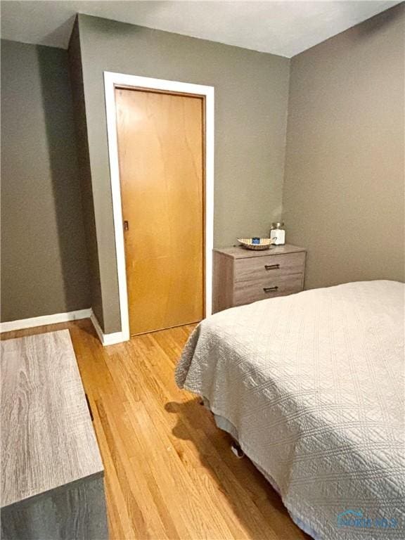 bedroom featuring light wood finished floors and baseboards
