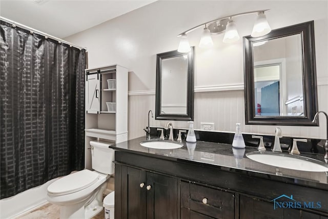 24203 W Reservation Line Rd, Curtice, OH 43412 - bathroom featuring double vanity, toilet, a sink, and a wainscoted wall