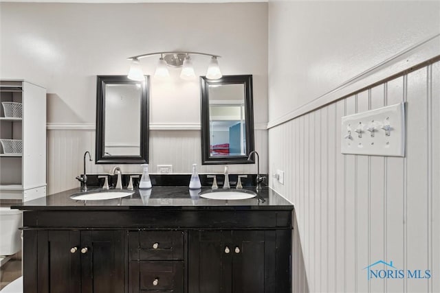 24203 W Reservation Line Rd, Curtice, OH 43412 - bathroom featuring double vanity, toilet, wainscoting, and a sink