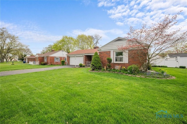 view of front of house featuring a front yard, a garage, driveway, brick siding, and fence