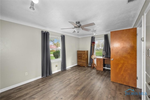 unfurnished bedroom with wood finished floors, baseboards, a ceiling fan, and multiple windows
