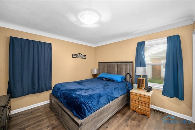 bedroom with dark wood-style floors, visible vents, and baseboards